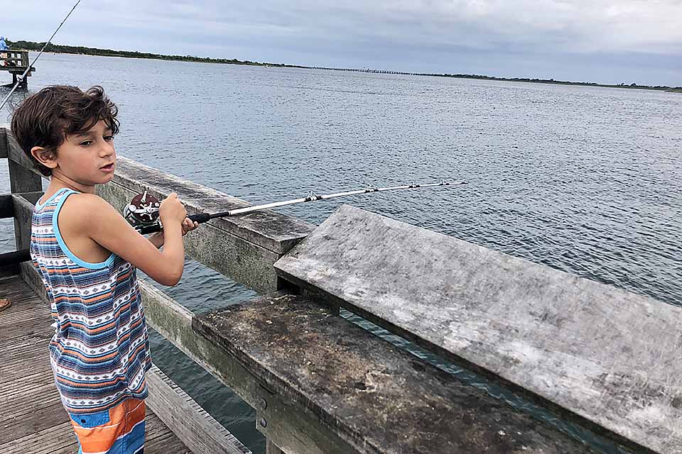 boy fishing off a pier