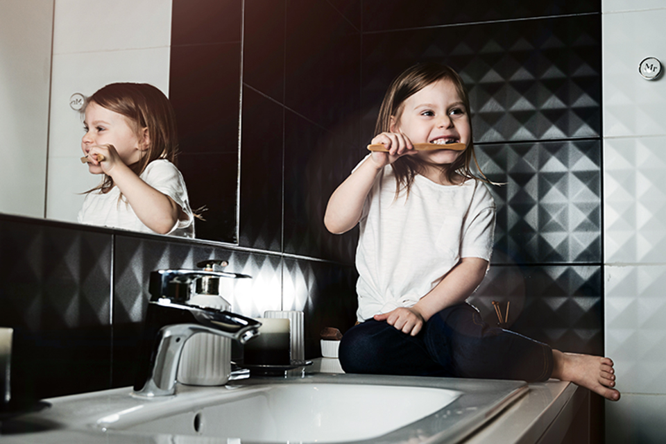 tricks for how kids can conserve water girl brushing her teeth at the sink