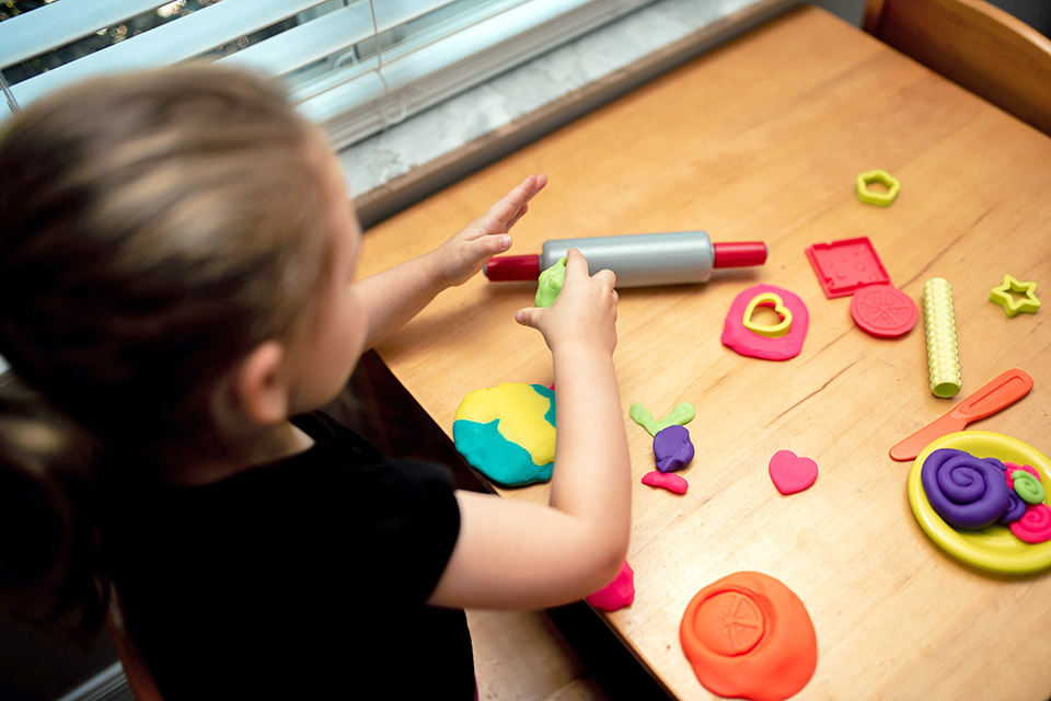 Girl playing with playdough to combat boredom.