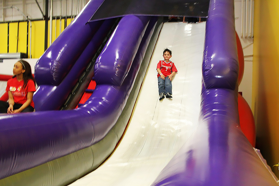 Boy sliding down a bouncy slide at BounceU, a trampoline park near NYC