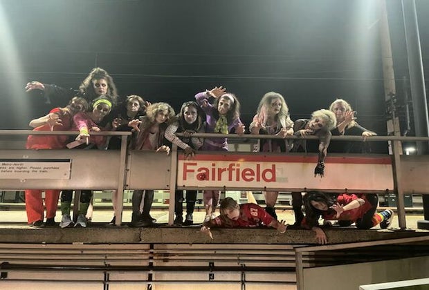 Image of MOMbies in zombie costume with Fairfield sign.