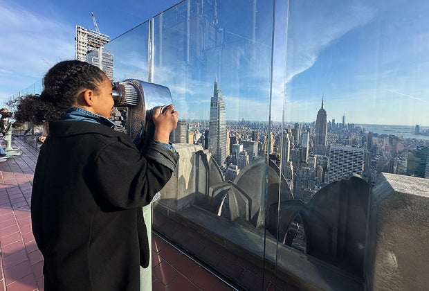 Rockefeller Center with Kids: Girl gazing out the skyline through a viewfinder
