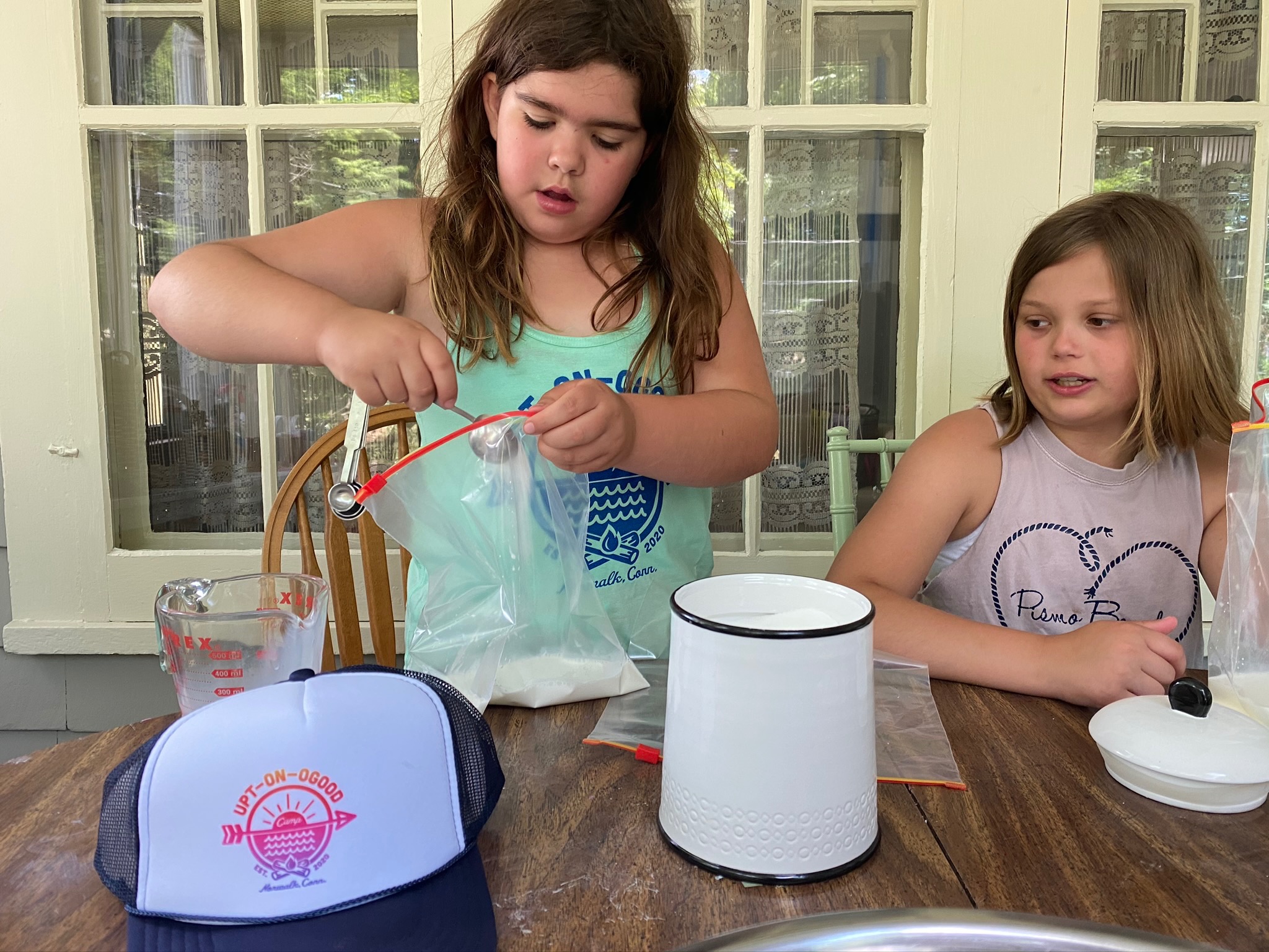 2 girls add ingredeints to make ice cream in a bag.