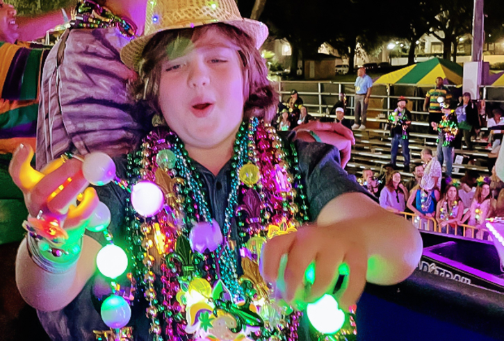 Boy plays with light up beads at a Mardi Gras Parade