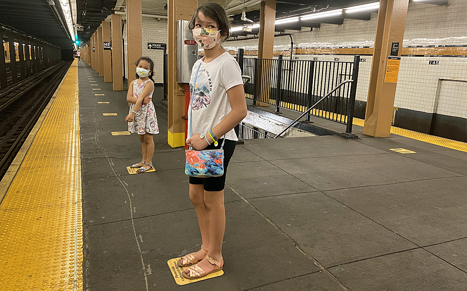 Two girls stand on empty New York City subway platform