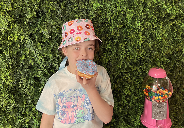 Kid eating a donut wearing a donut hat - Photo by Kelly Patino for Mommy Poppins National Donut Day