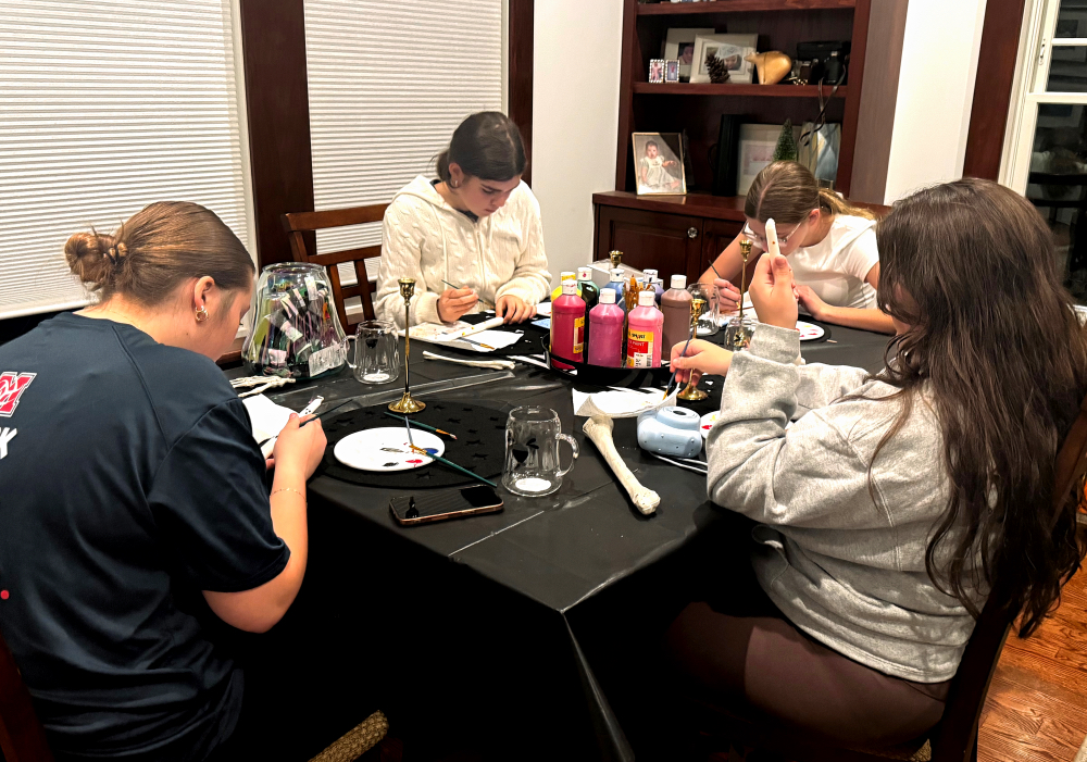 4 teen girls sit around a table, painting crafts