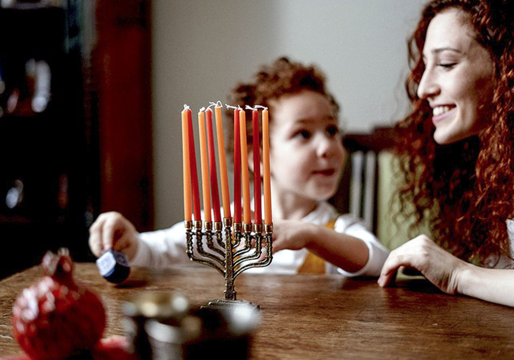Child lighting candles for Hanukkah on a menorah